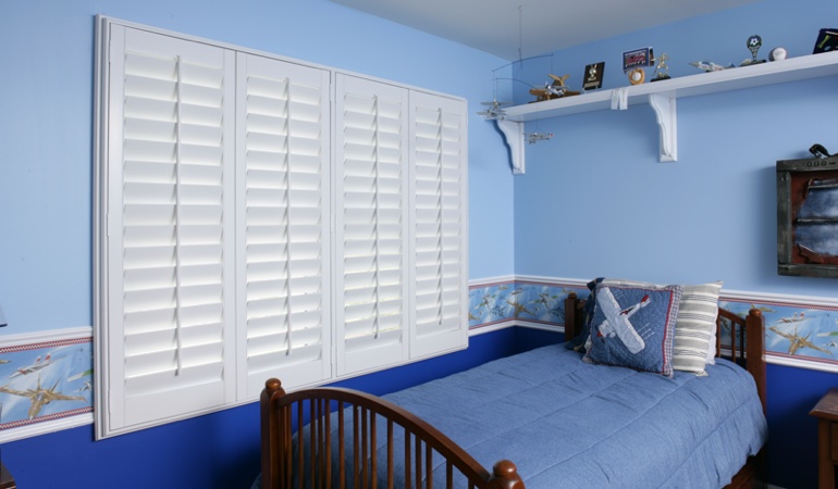 Large plantation shutters covering window in blue kids bedroom in Philadelphia 
